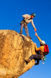 Rock climbing team reaching the summit.